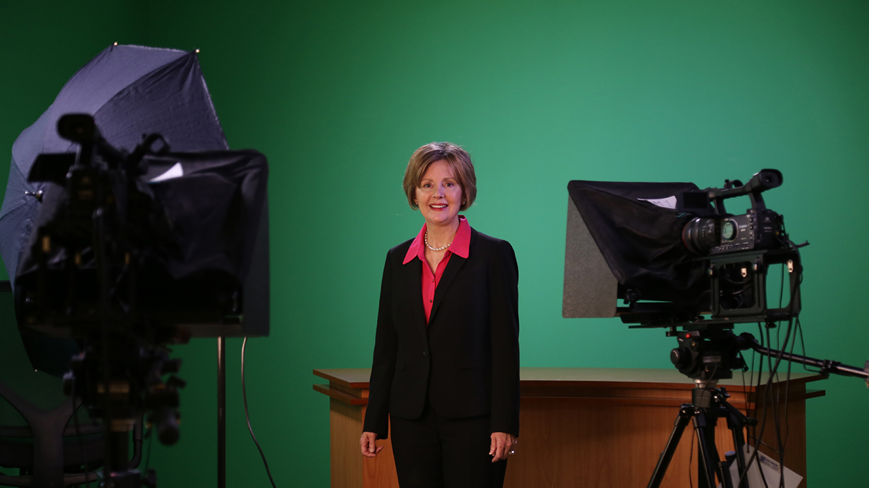 Angela Powers in the newsroom in front of a green screen.