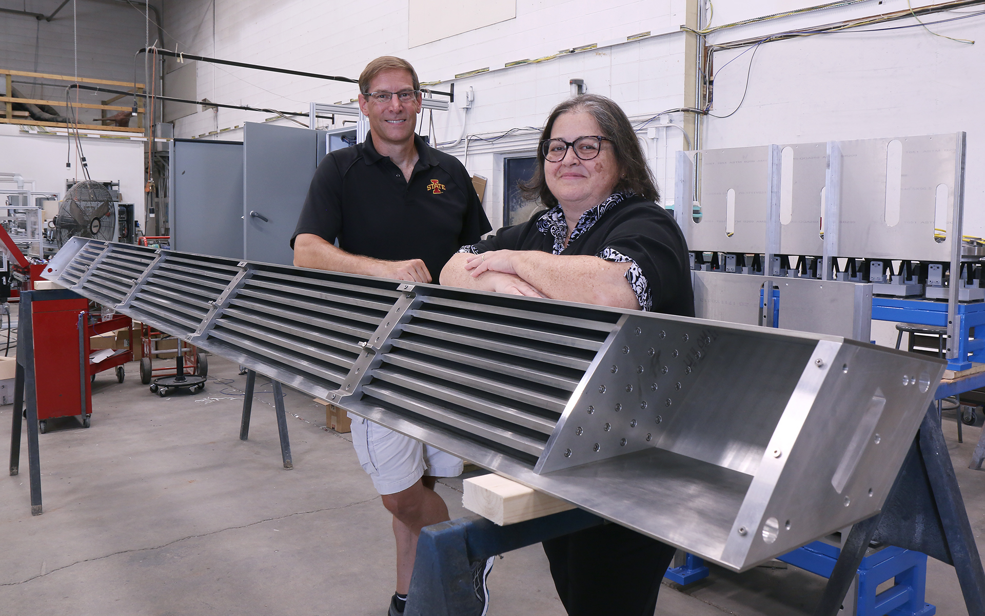 A man and woman stand by metal equipment.