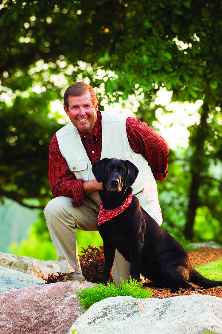 a man kneels outside with his dog