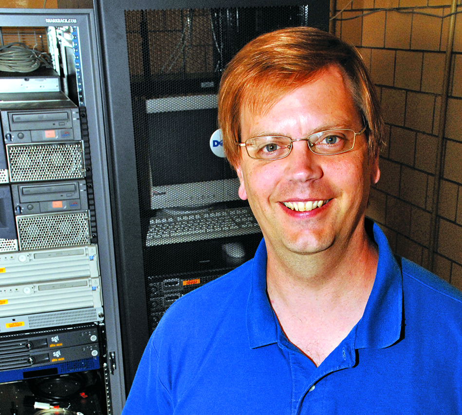 Dr. Tom Holme standing in front of computers.