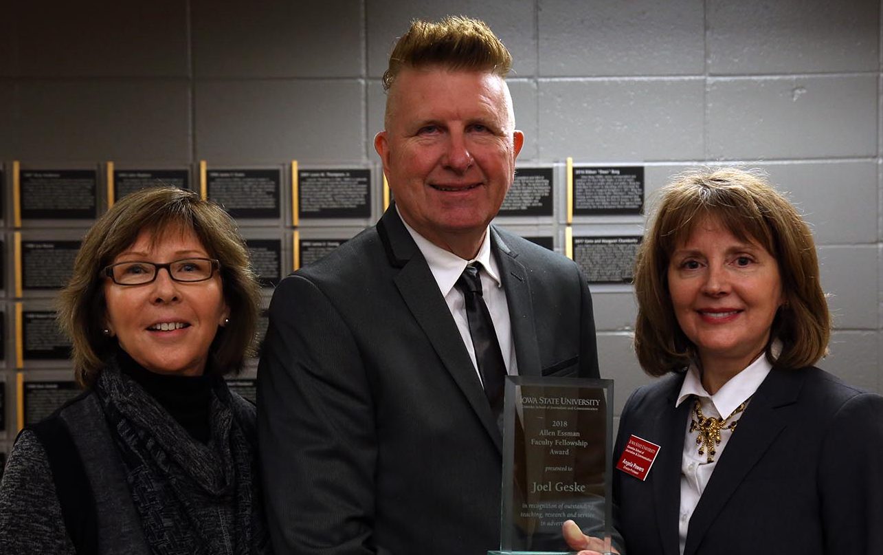 Joel Geske holding award, between two others.