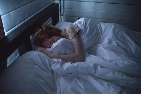 Woman sleeping with white blankets and pillows