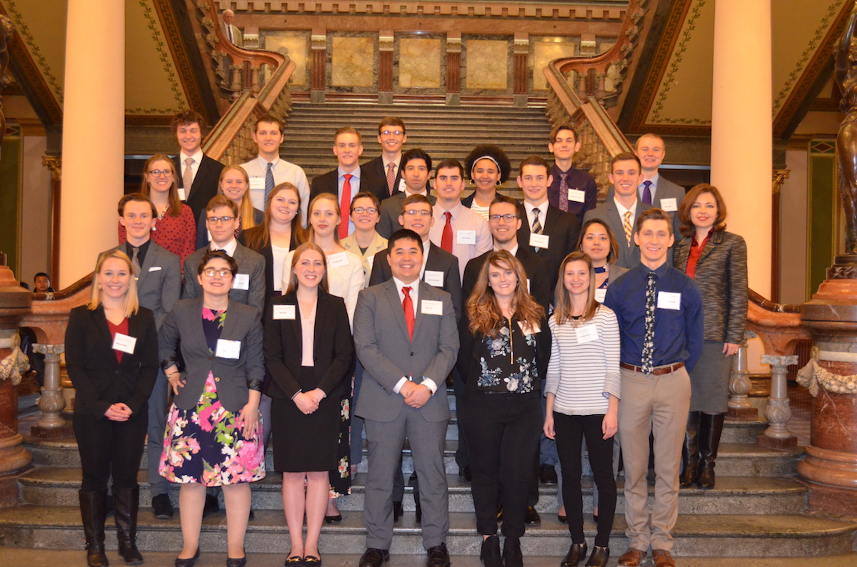 Group of college students in business attire standing on a staircase.