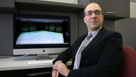 Borzoo Bonakdarpour sitting in front of computer monitor.