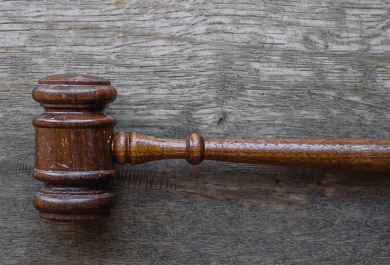 Judge's gavel on wood grain background.