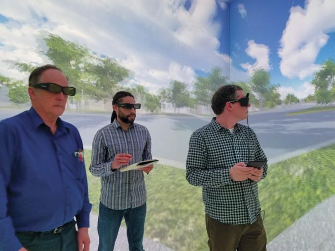 Kofi and colleagues with virtual reality goggles on in front of outdoor scene backdrop