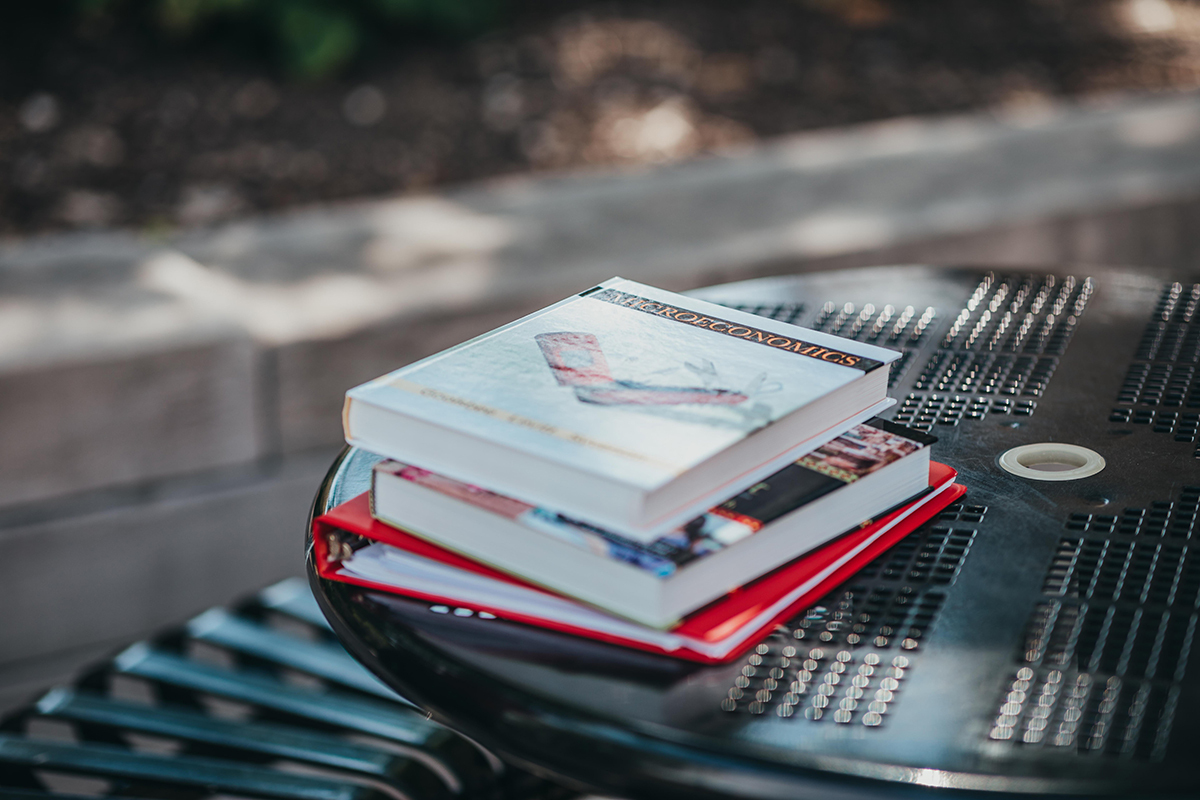 stack of books sits outdoors on a table