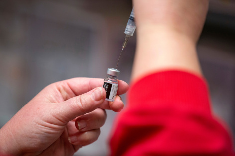 A medical professional loads a syringe with a vaccine