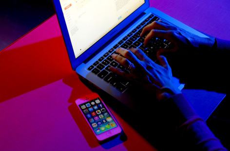 Person types on a laptop with an illuminated screen