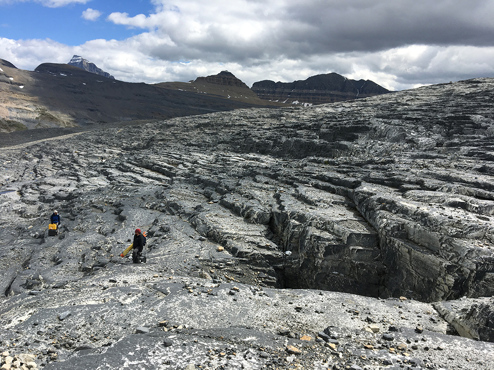 Researchers measure an exposed glacier bed in the Rocky Mountains.