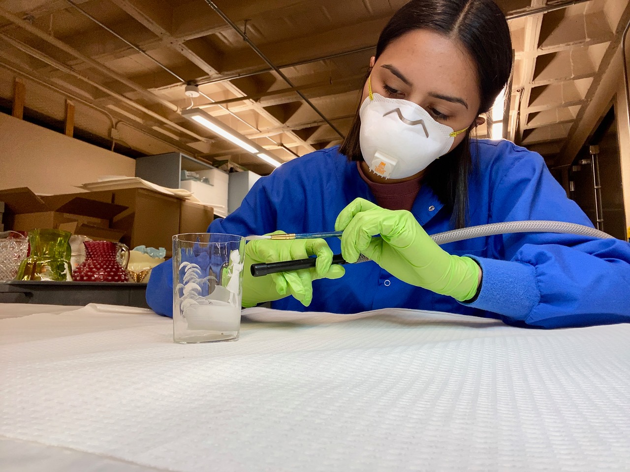 Madisyn Rostro cleans a glass museum object