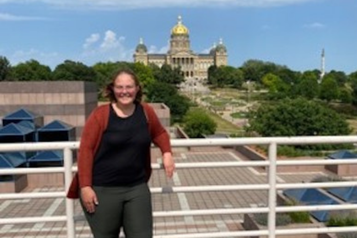 Person leaning against railing, Iowa Capitol in background