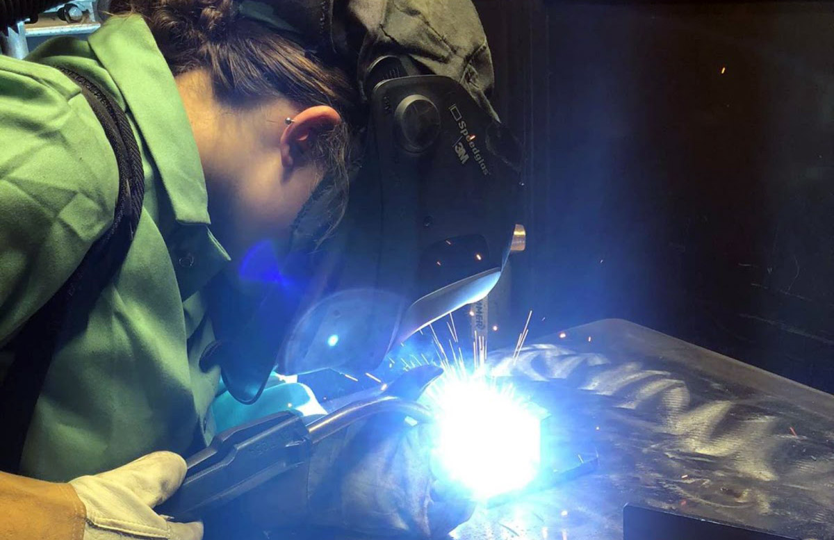 Woman welding metal with goggles