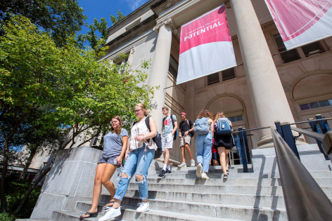 ISU students walk down the steps of a campus building on a sunny day