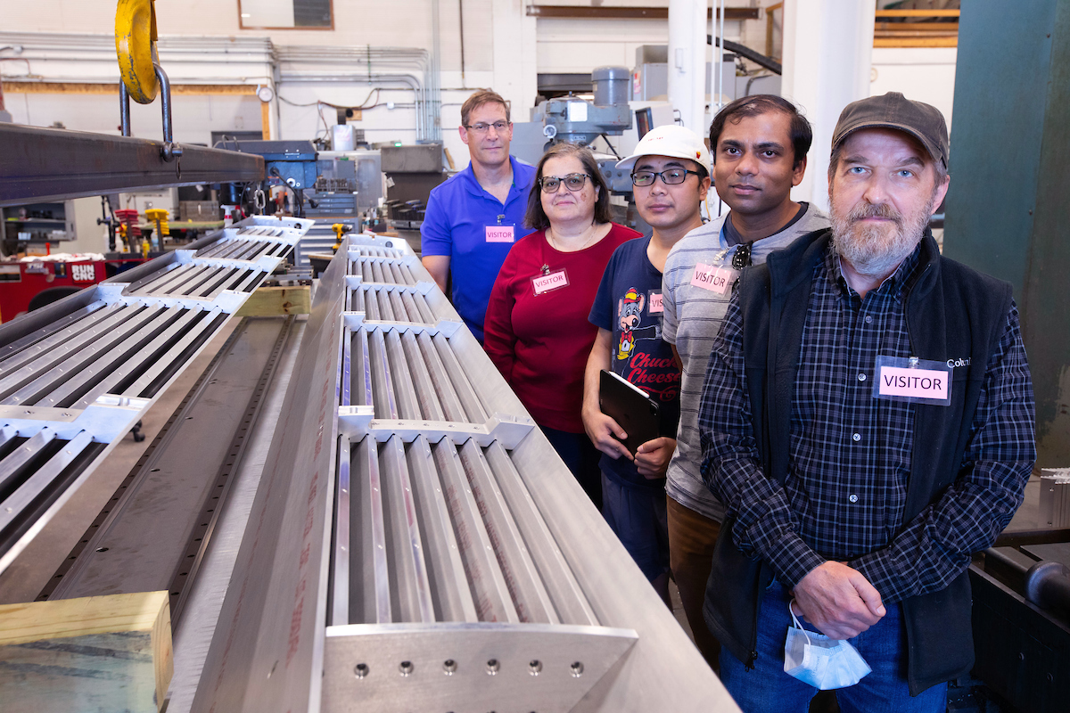 Iowa State physicists stand next to large aluminum frames that will be used in an experiment