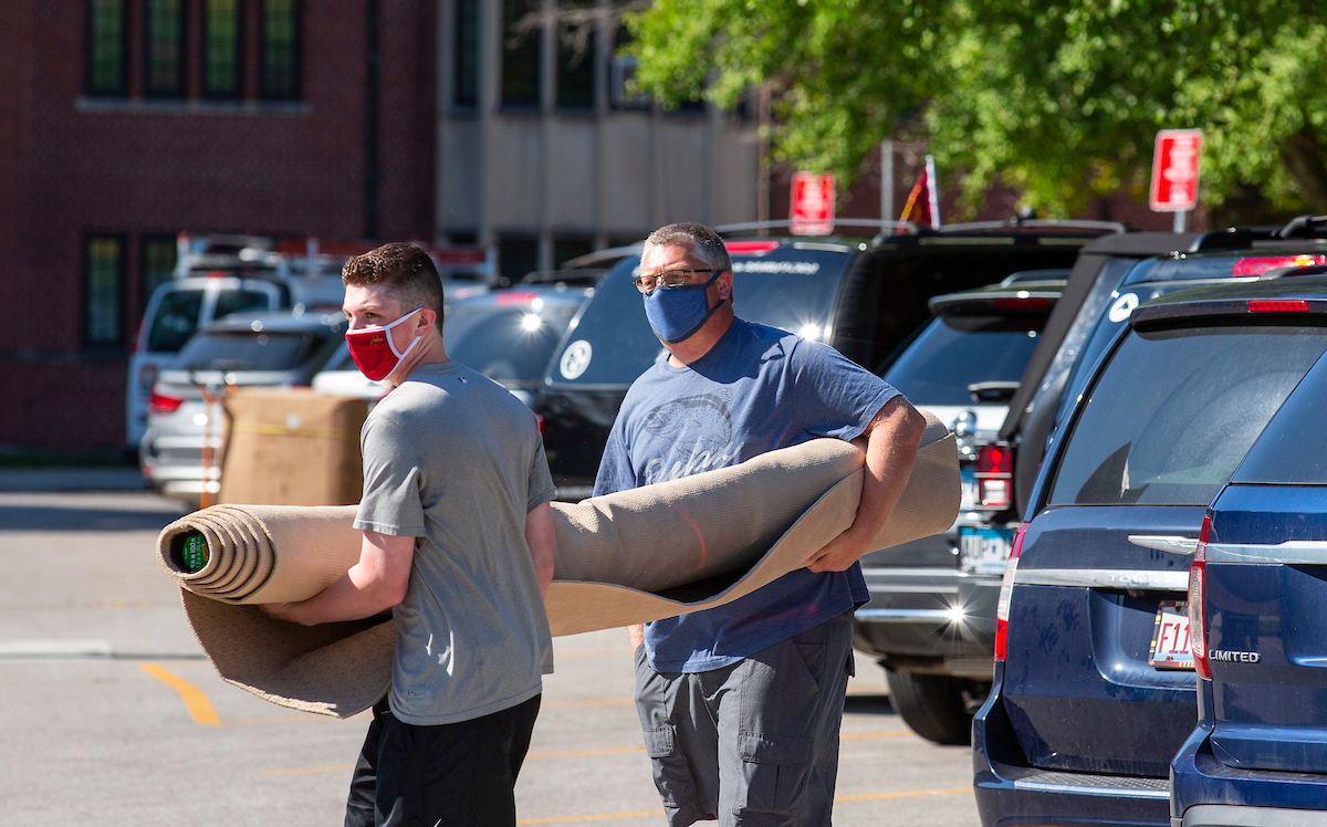 Father and son carry items into dorm on college move-in day