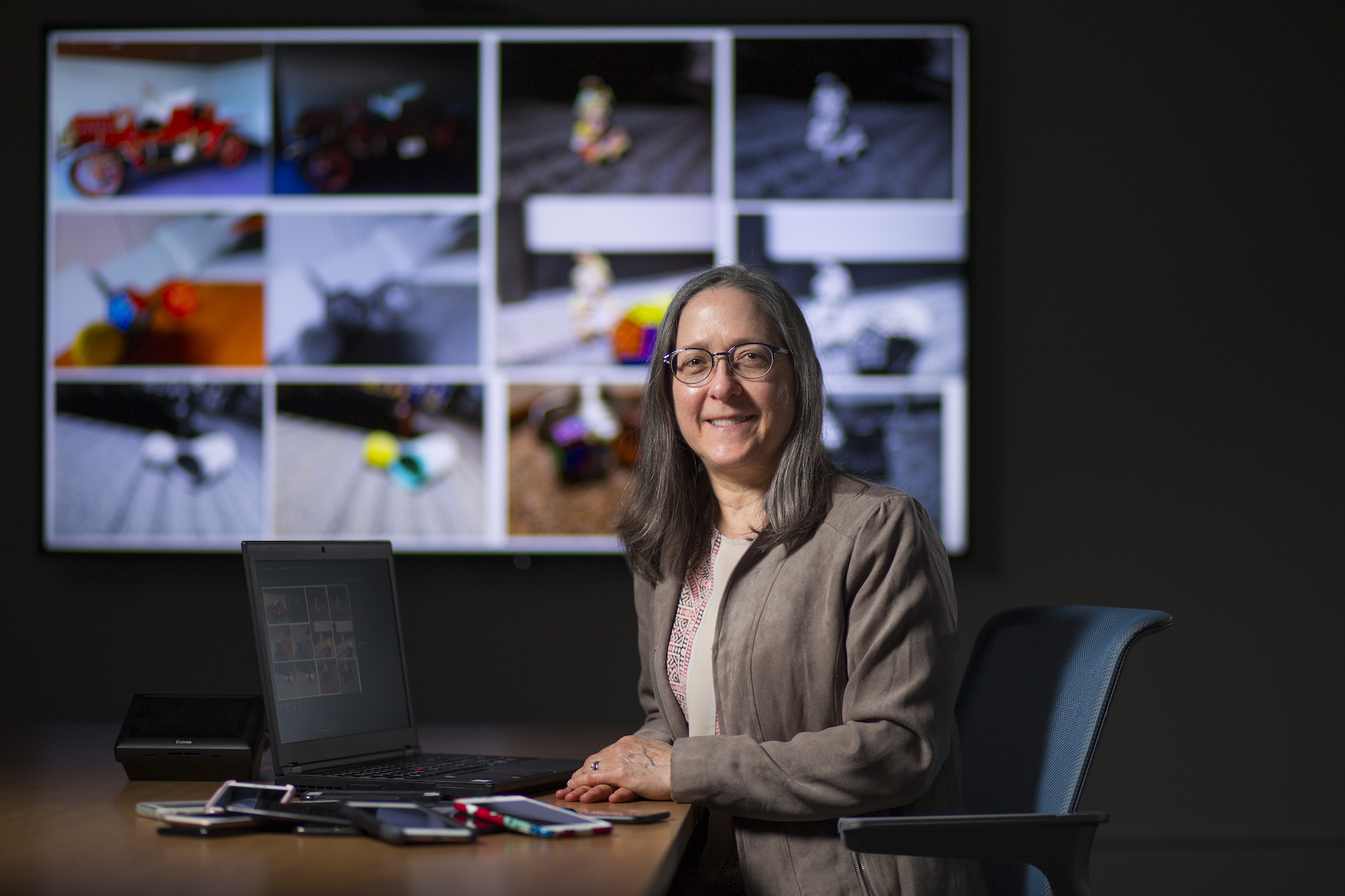 Jennifer Newman sits at a table with forensic images in the background