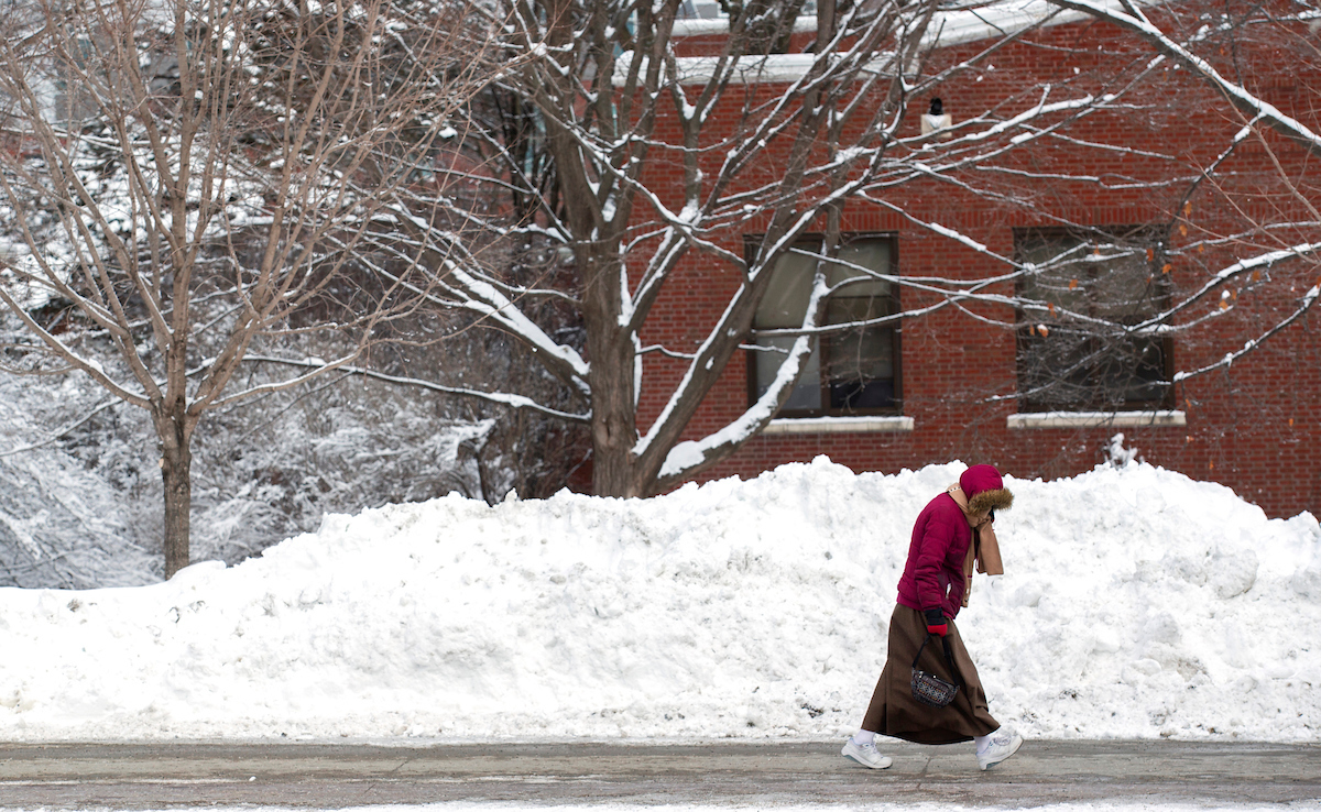 A student walks through campus on a snowy day