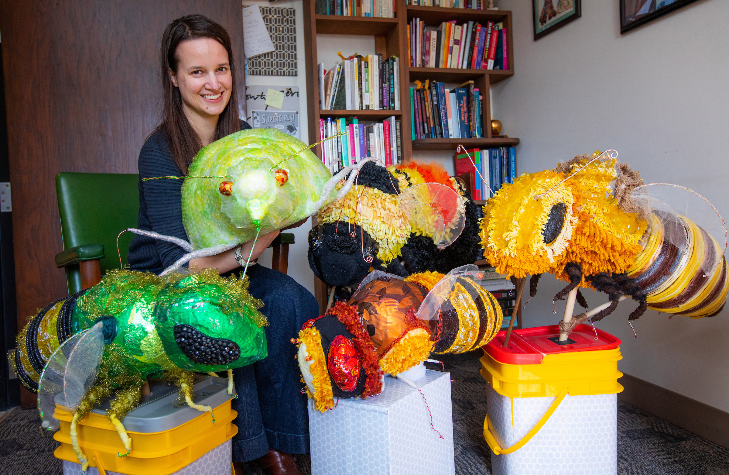 Associate Professor Amanda Petefish-Schrag poses with large, colorful insect puppets