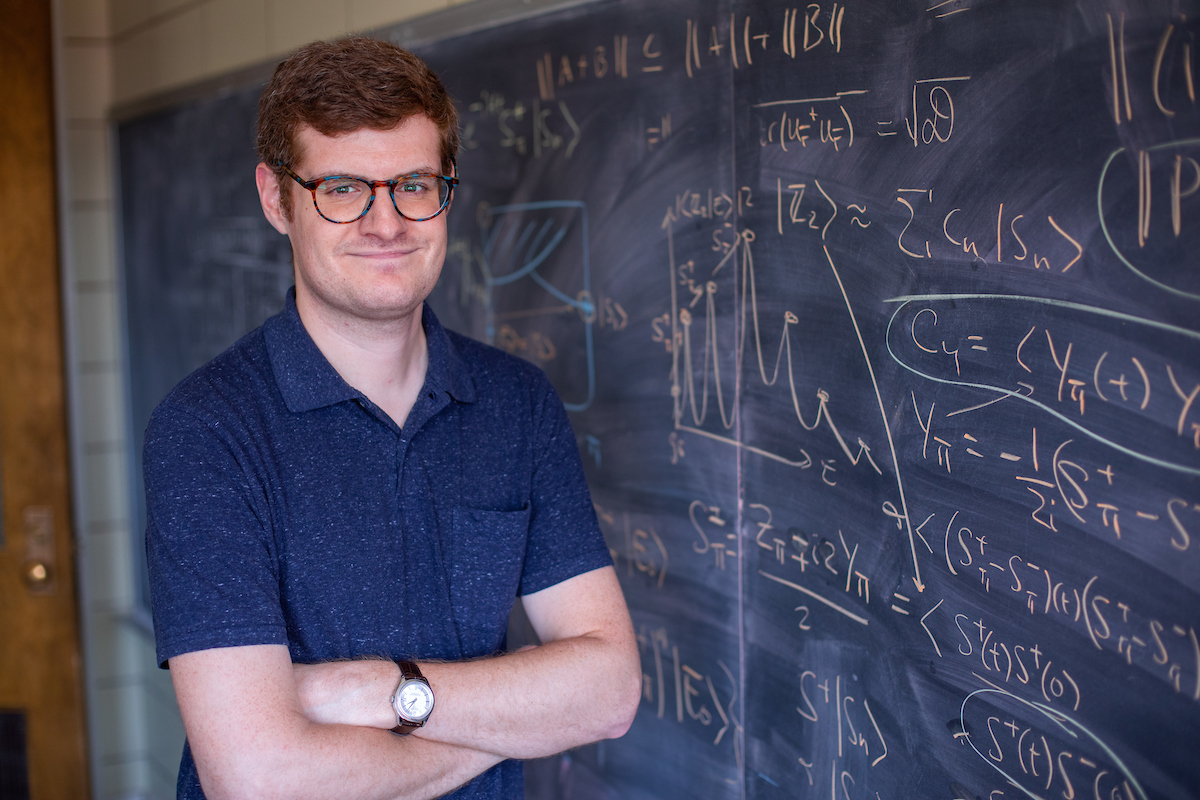 Thomas Iadecola poses in front of a blackboard filled with computations