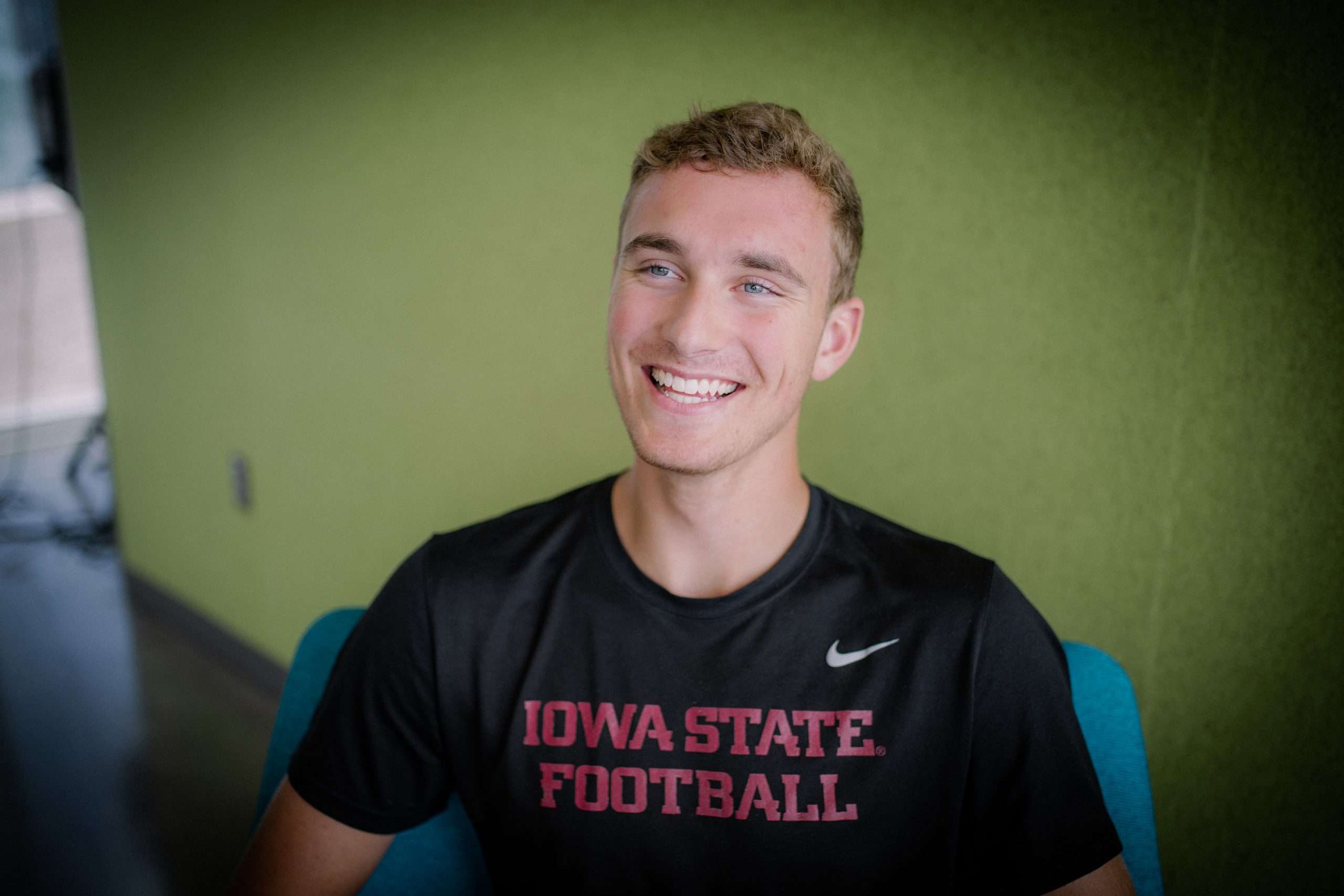 Student Jacob Kautman smile against a green backdrop