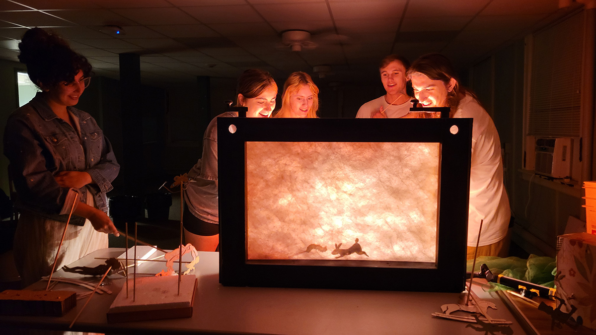 Students stand next to a shadow box for use during the production of "The Velveteen Rabbit."