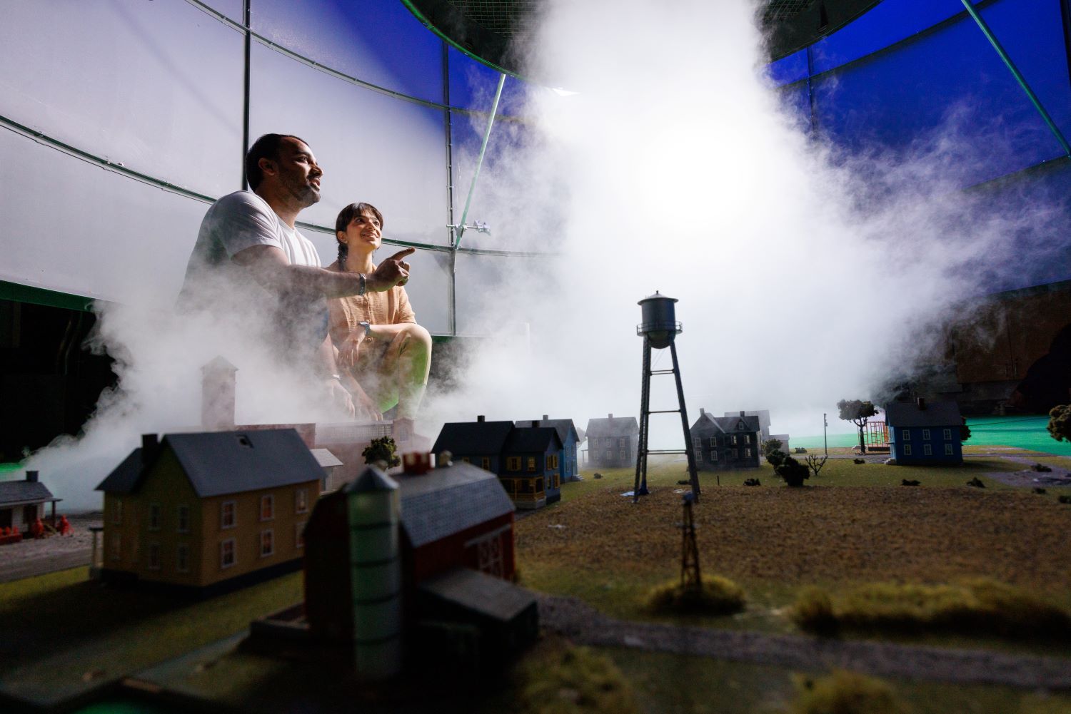 Two people looking at a tornado simulator.