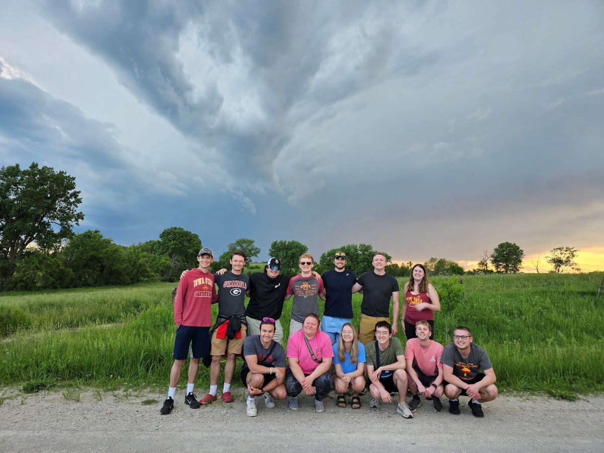 Student group poses in front of field and stormy skies