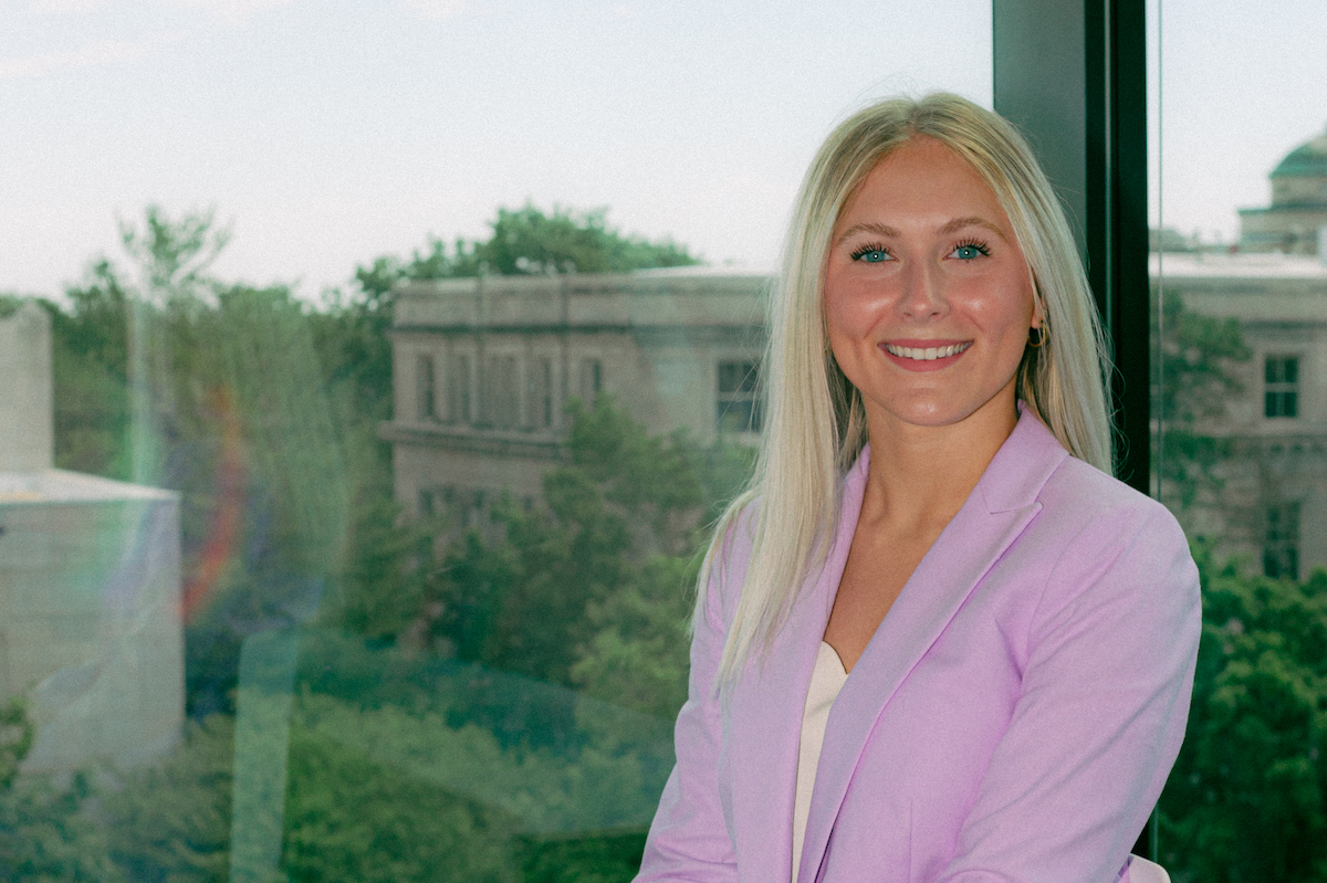 Student headshot in front of building window overlooking campus