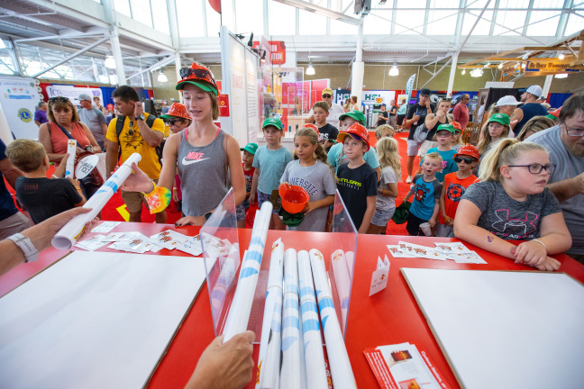 Visitors receive Iowa State athletics posters at the 2023 Iowa State Fair.