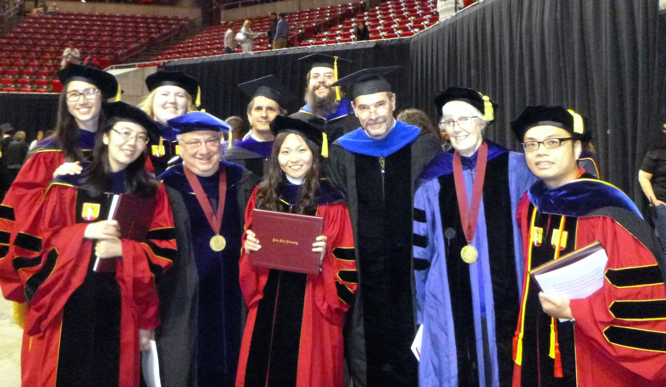Graduate students and faculty pose in Hilton Coliseum at graduation.