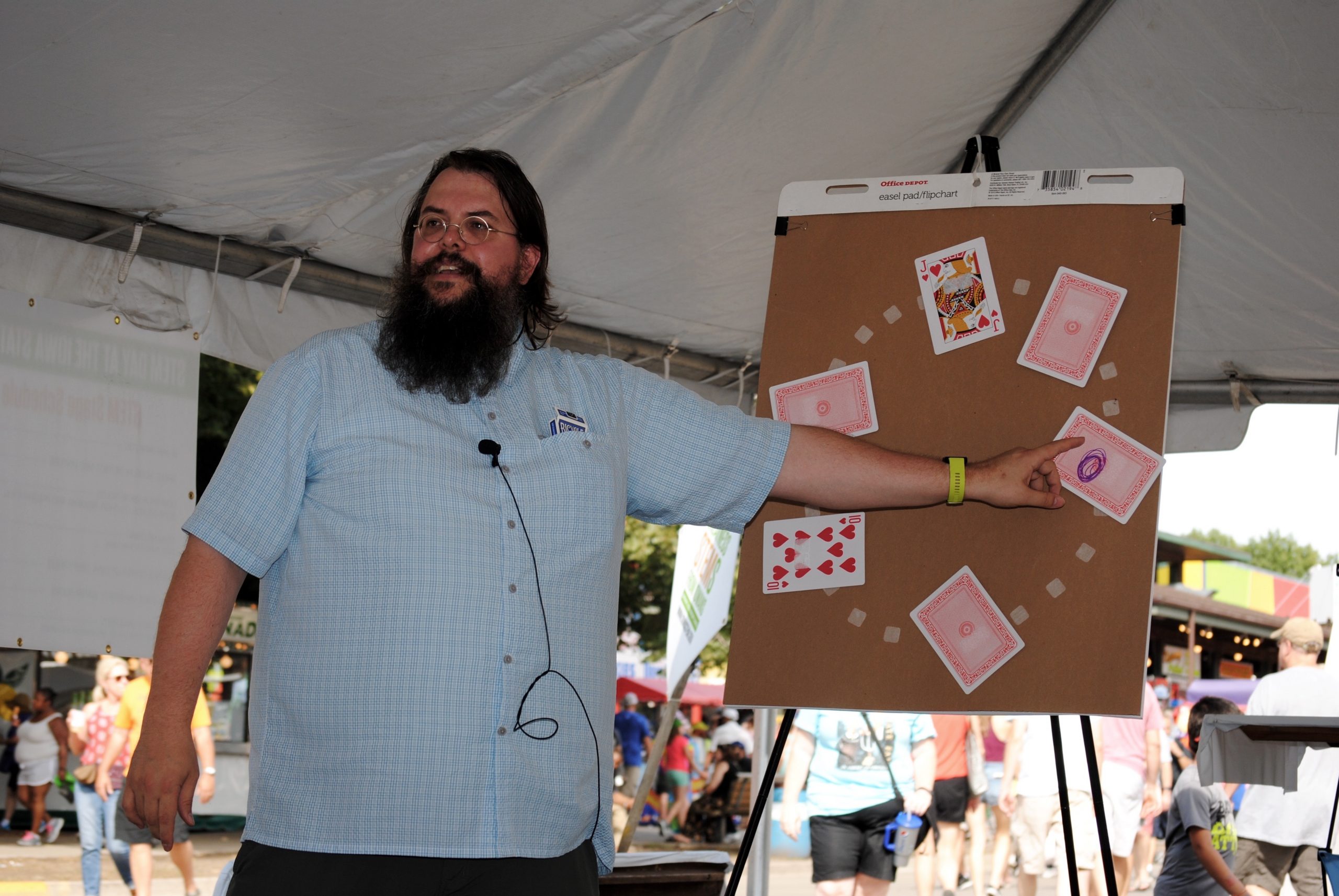 Steve Butler points to large cards on a cardboard display in a tent at the State Fair.