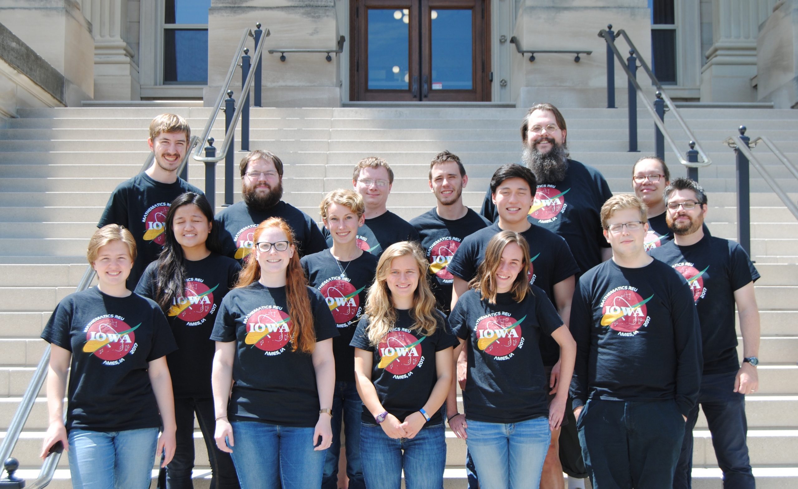 Students from the Mathematics Research Experience for Undergraduates pose on the steps of Beardshear Hall with faculty James Rossmanith and Steve Butler.