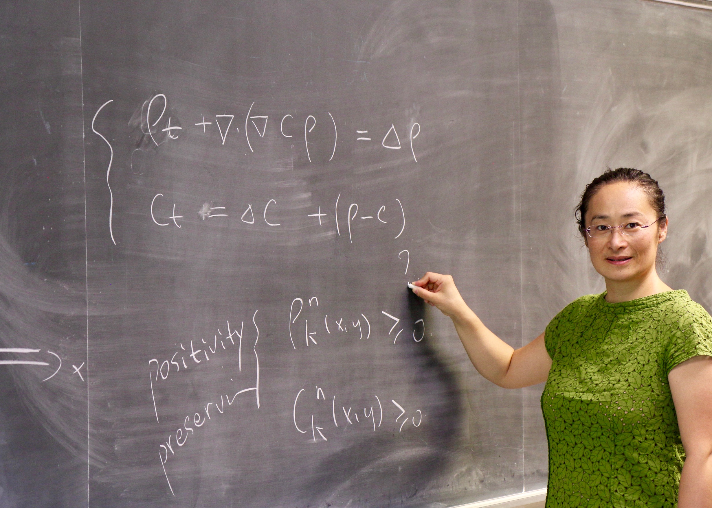 Jue Yan performing mathematical computations at a blackboard.