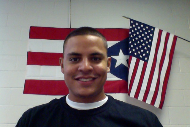 Portrait photo of Neftali Lopez Duprey with the American Flag behind him.