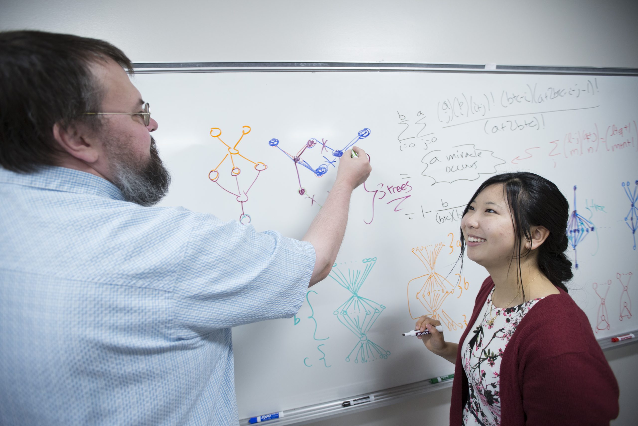 A math professor and female student at a whiteboard.