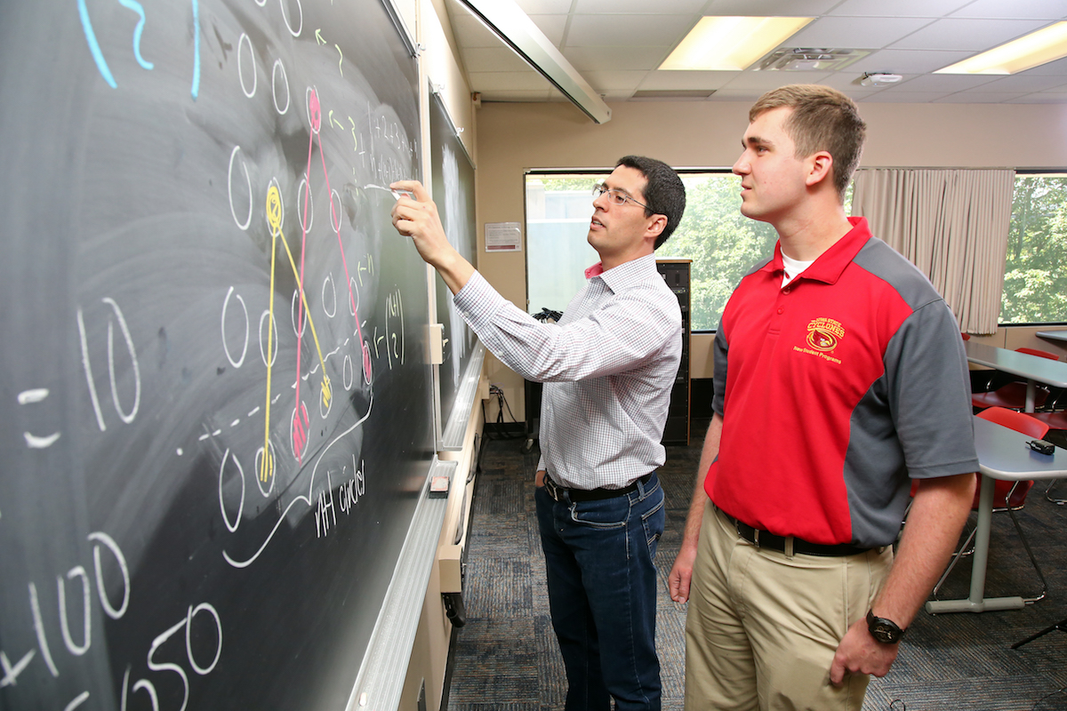 A math professor and a student working at a chalkboard.