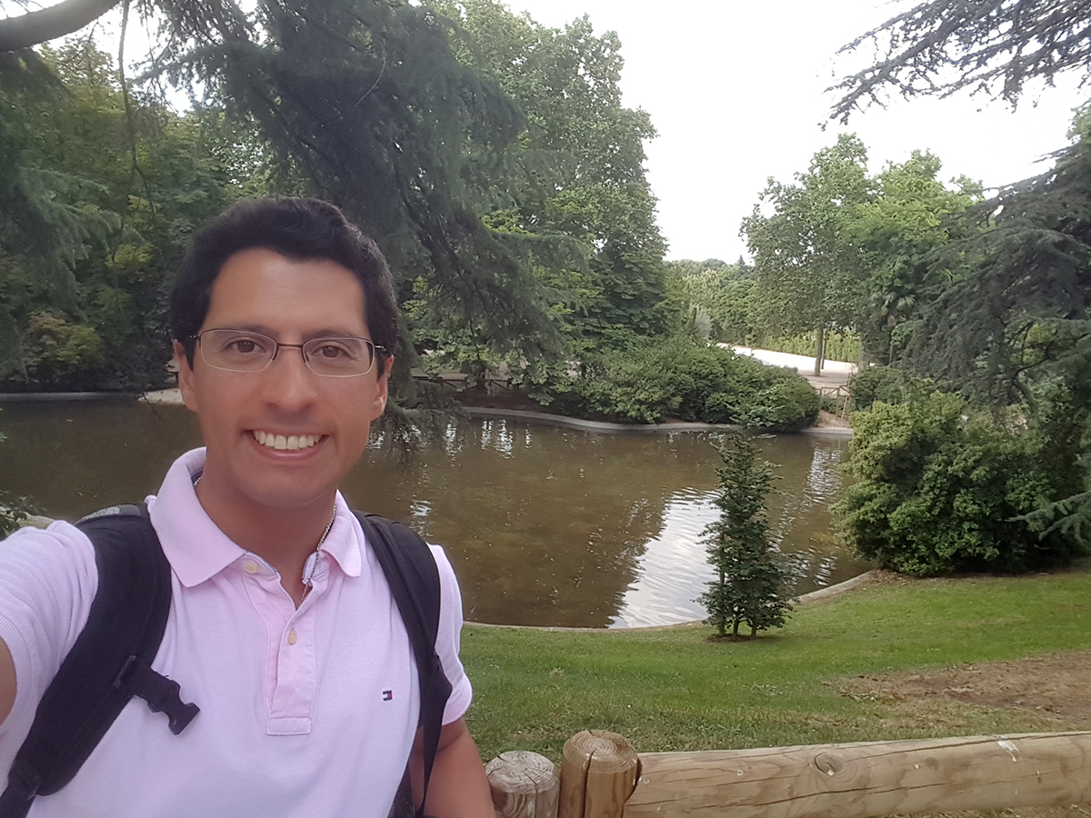 Pablo Stinga stands in front of trees and small body of water.