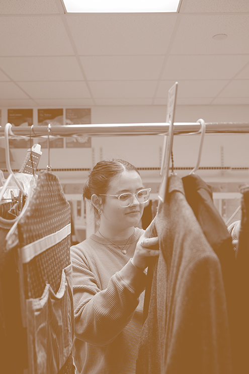 Student looks through coats on garment rack