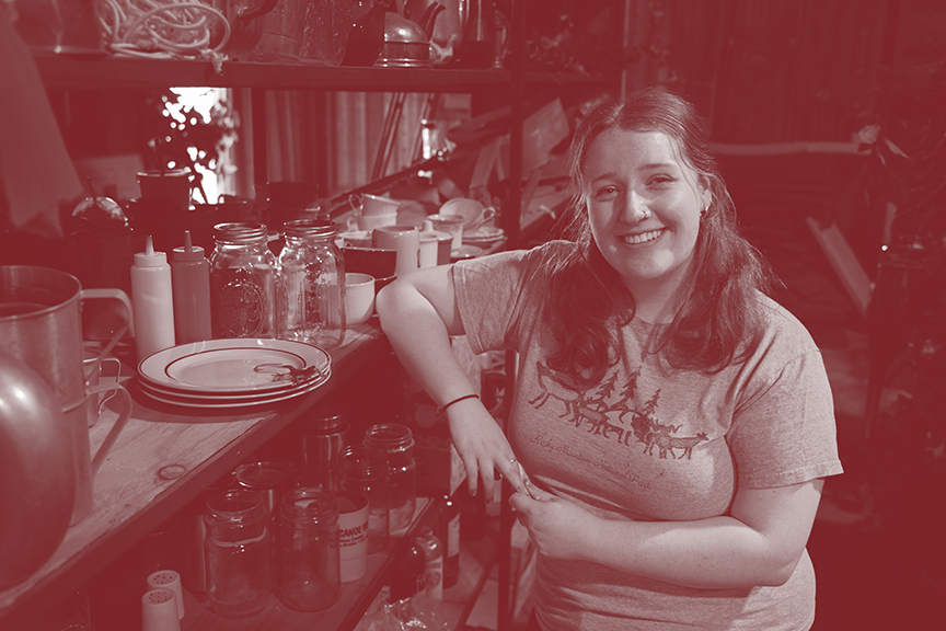 Student poses next to shelves of kitchen props