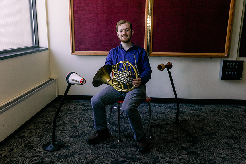 Jarod Hart with his French horn and a mute stand.